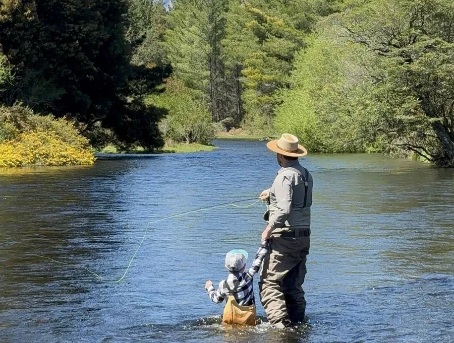 Padre e hijo vadeando juntos un río durante el taller Padres e Hijos