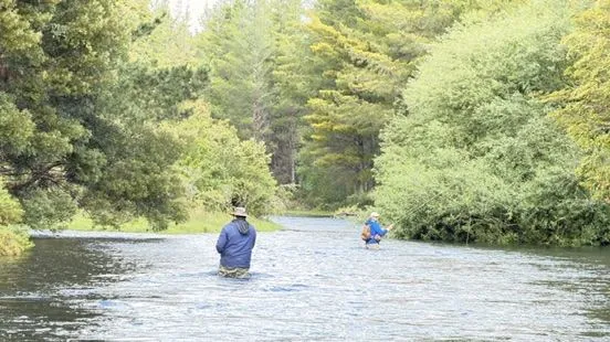Dos pescadores con mosca vadeando un río de la zona